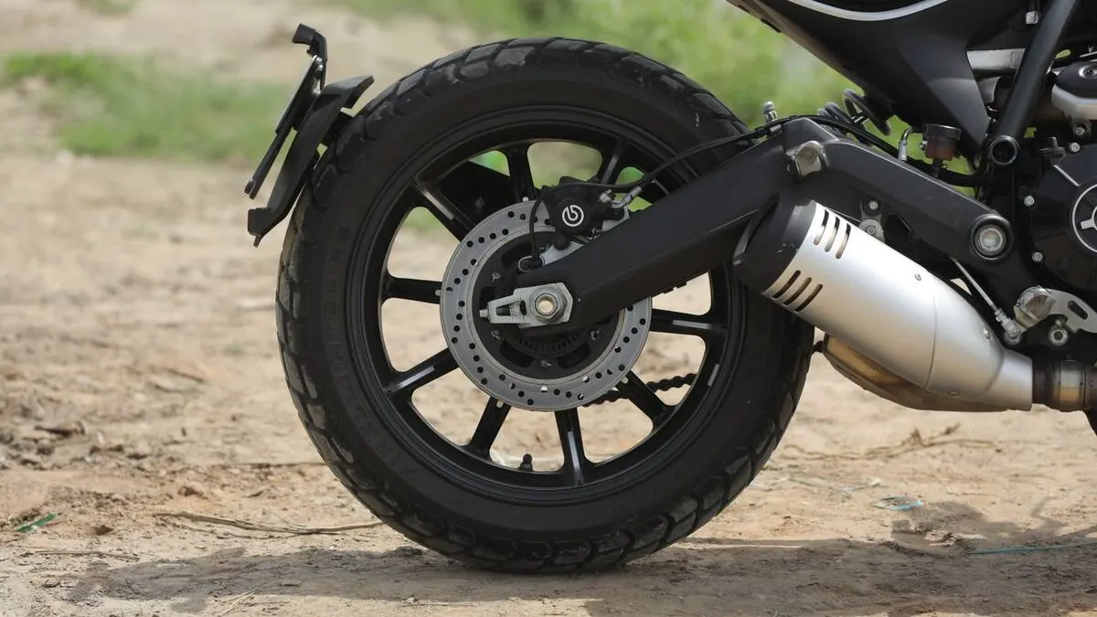 Gros plan sur la bande de roulement d'un pneu de moto, témoins d'usure et gomme craquelée