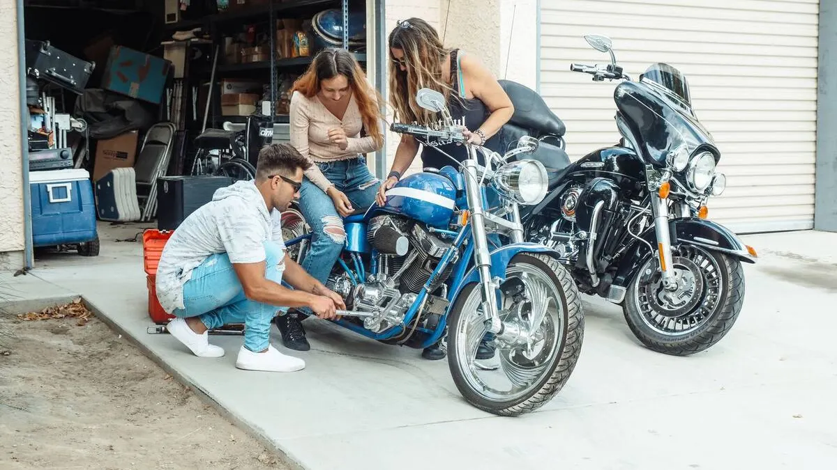 Moto couverte de poussière dans un garage, batterie en charge et pneus vérifiés avant la première sortie